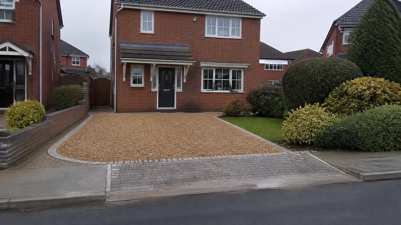 Golden gravel driveway with a granite sett edge and a solid apron in front of a brick detached house