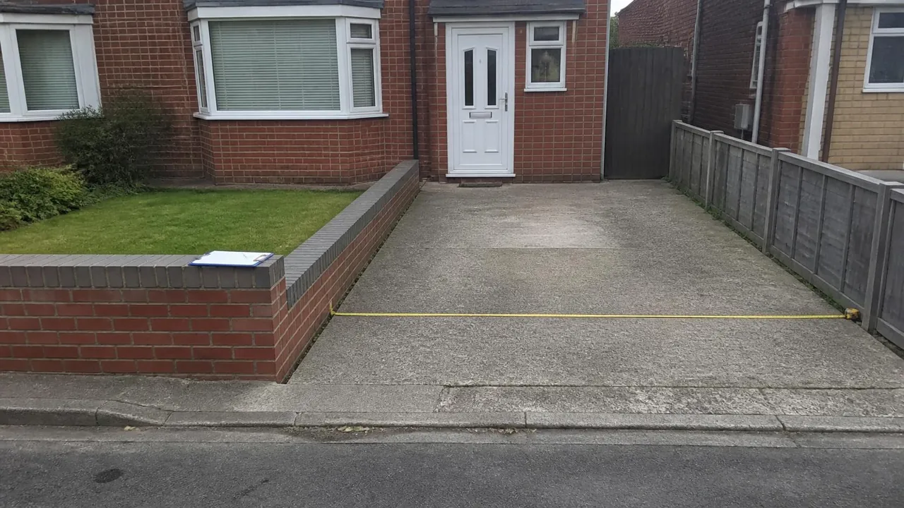 Tape measure across an old concrete drive, the first step in pricing a new driveway