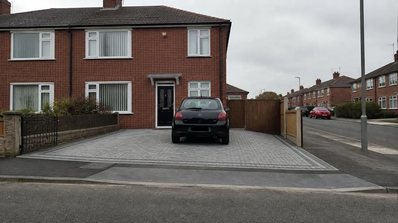 Block paved drive leading to a dropped kerb across the pavement outside a 1960s semi