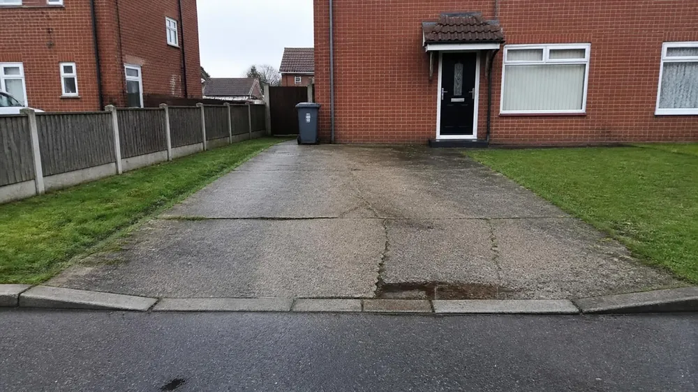 Example image: old concrete driveway cracked across the middle with weeds in the joints